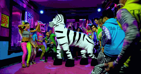 Image of a dance party filled with people and two people in a single zebra costume, dancing